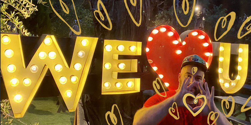 A man standing in front of a sign that says we love you.