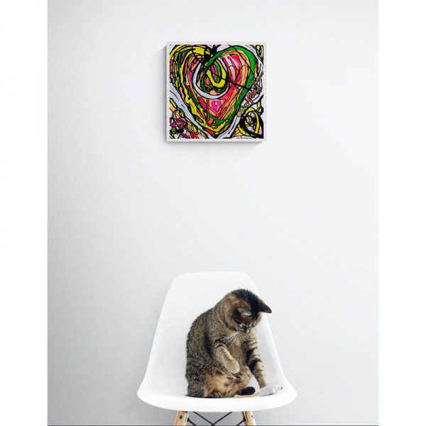 A cat sits on a white chair in front of an Infinity Heart Print.