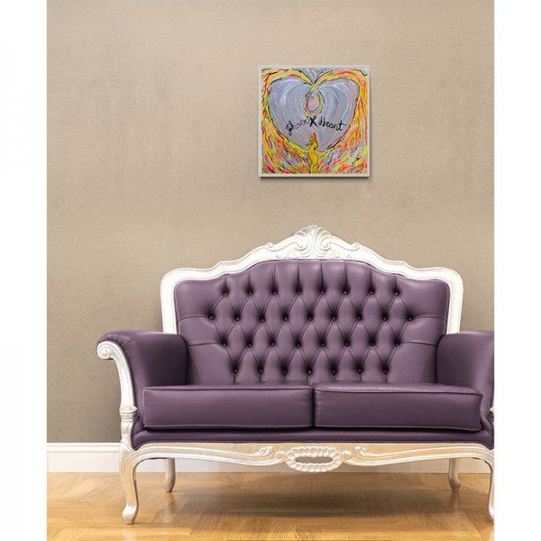 A purple couch in a room with a Phoenix Heart Framed Print on the wall.