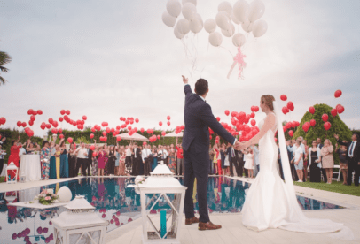 A couple is holding balloons while standing outside.