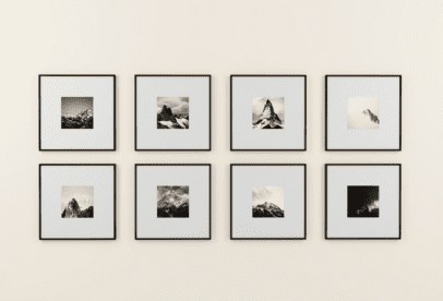 A wall with eight framed photographs of mountains.