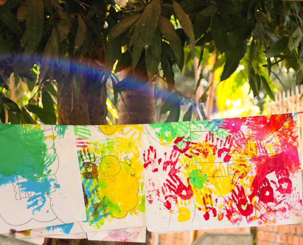 A group of children 's paintings hanging on a tree.